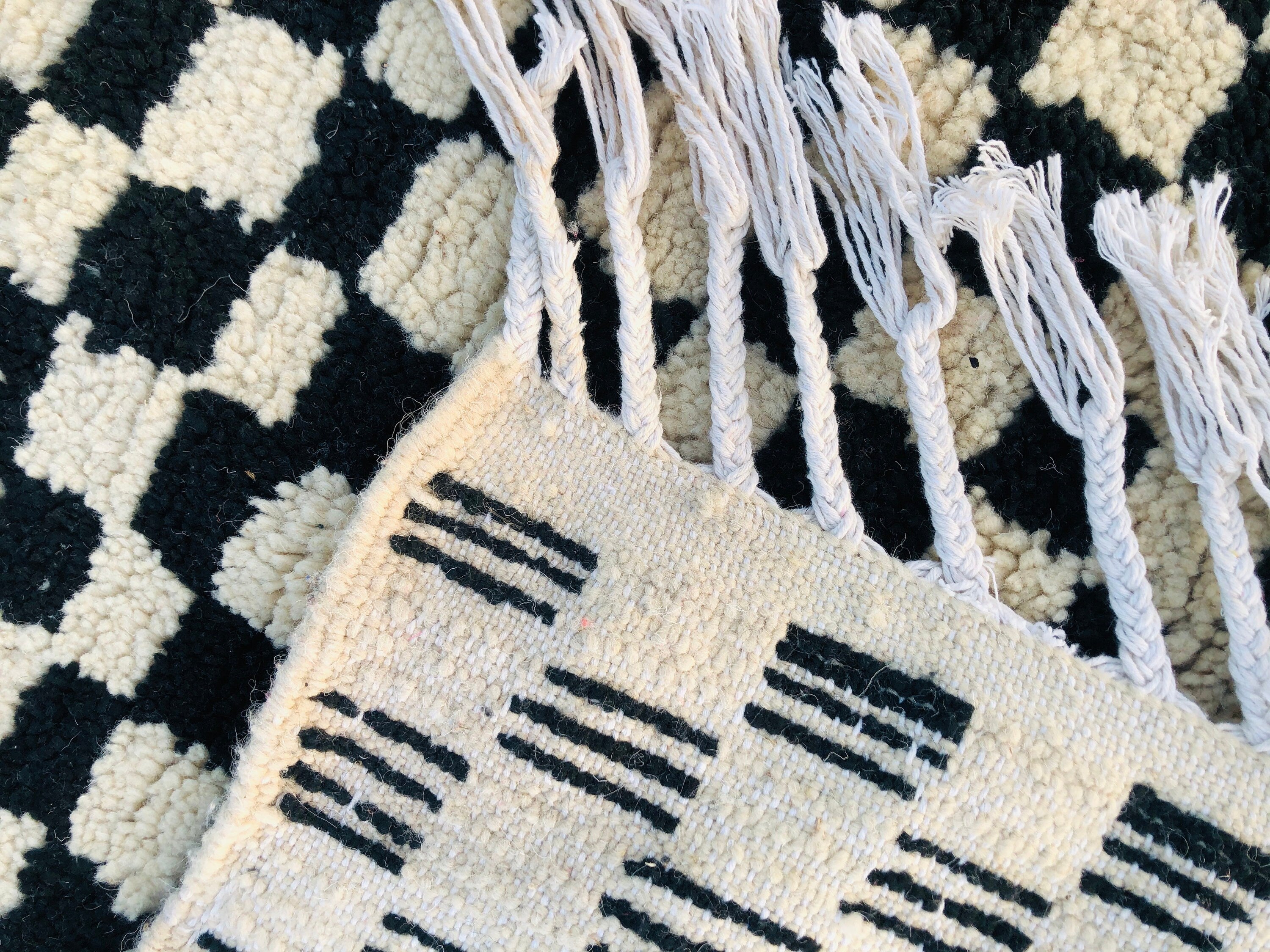 Handwoven black and white patterned rug with fringes, perfect for home decor.