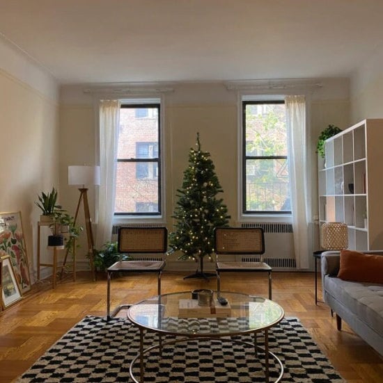 Cozy living room with Christmas tree, plants, and stylish furniture for holiday warmth.