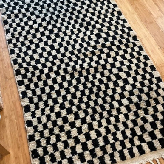 Checkered black and white rug on wooden floor, ideal for modern home decor.