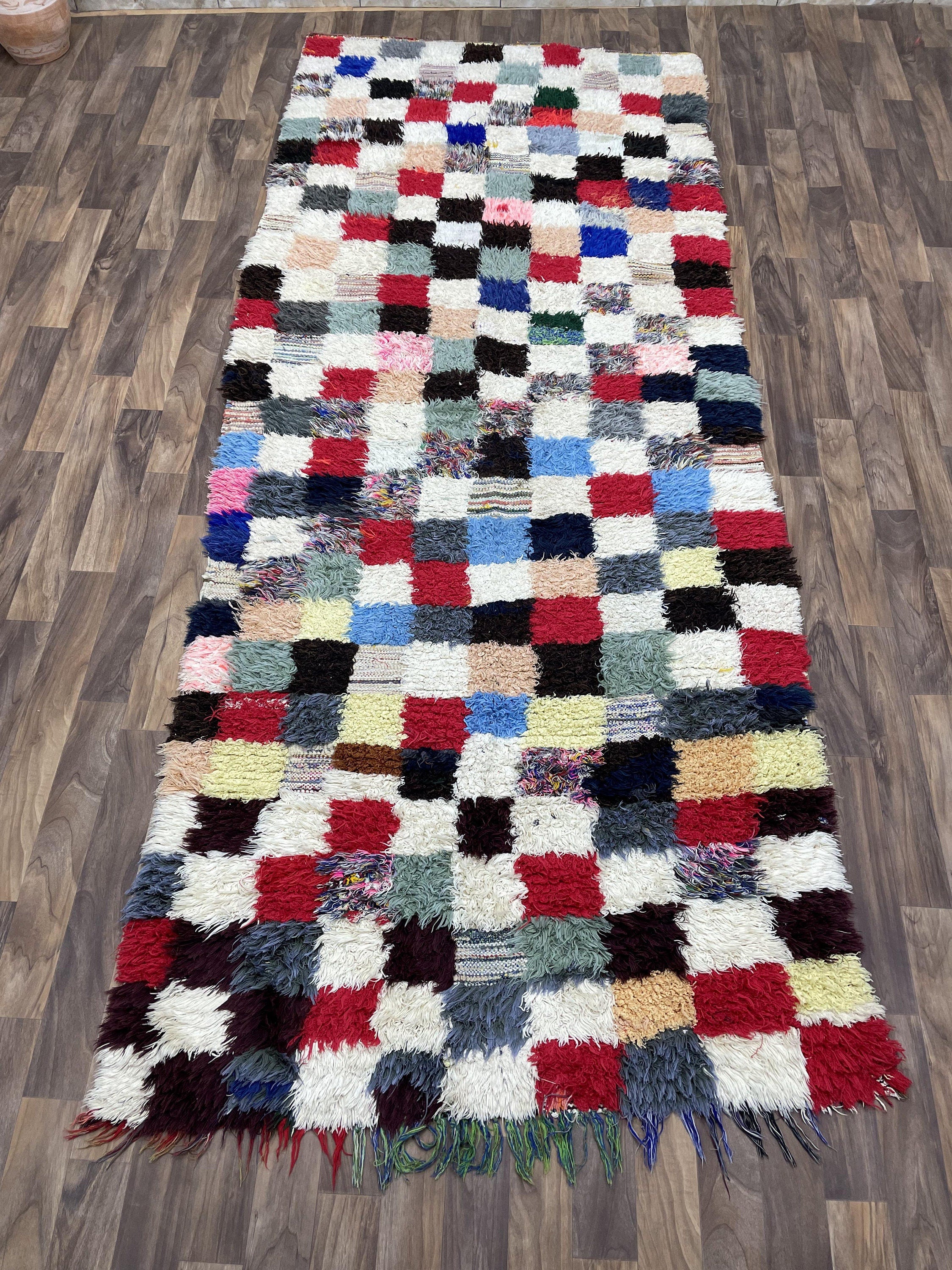 Colorful patterned shag rug with squares in red, blue, and neutral tones for cozy decor.