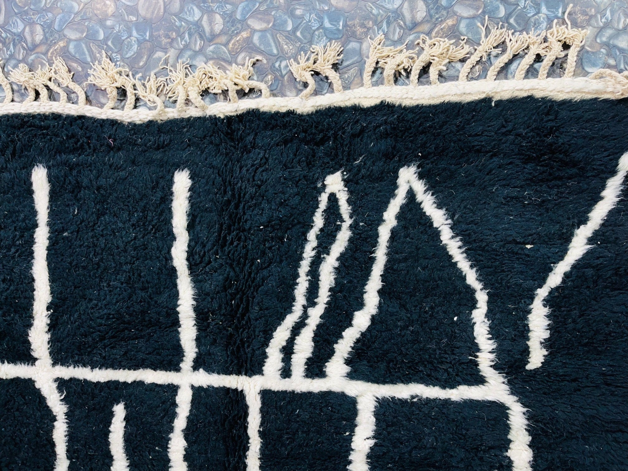 black and white patterned rug on stones