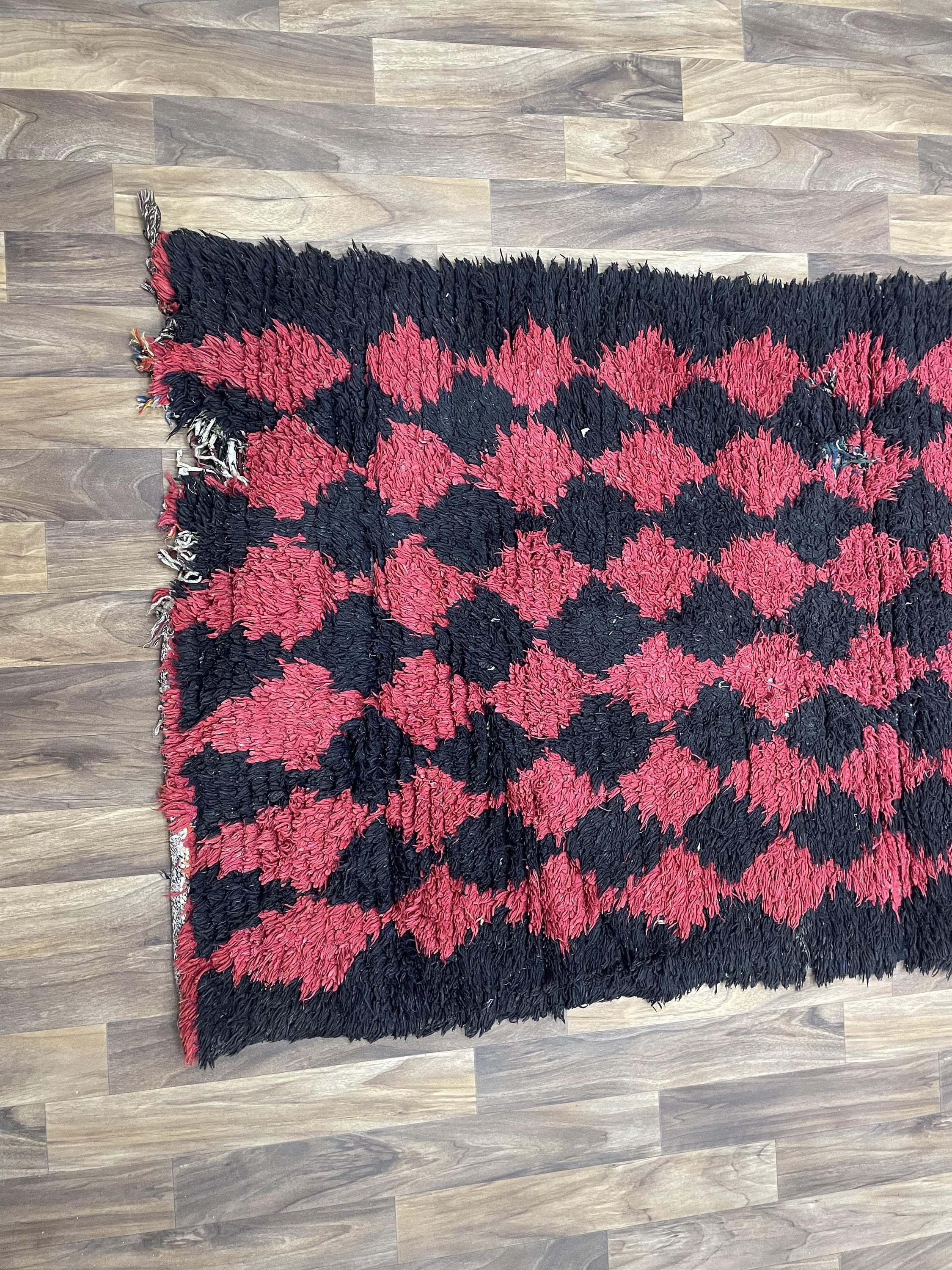 Handwoven black and red diamond-patterned rug, perfect for enhancing home decor style.