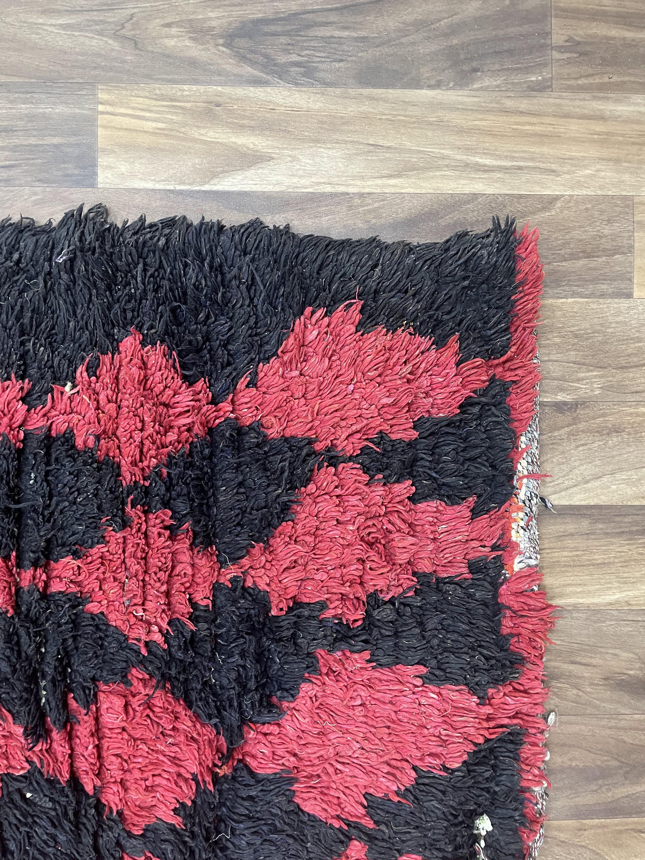 Red and black textured rug with a unique geometric pattern for home decor.