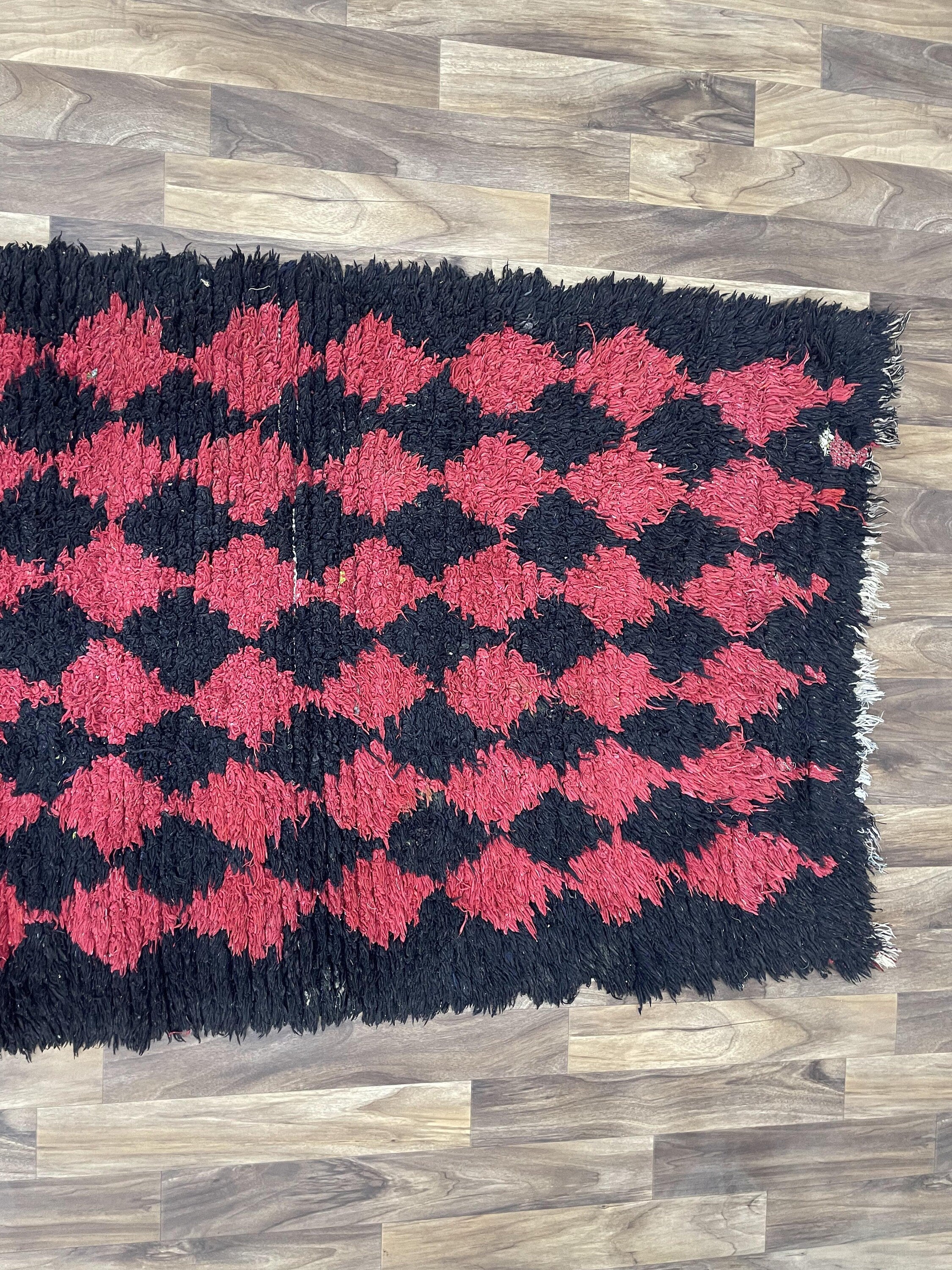 Handwoven red and black diamond pattern rug, perfect for stylish home decor.