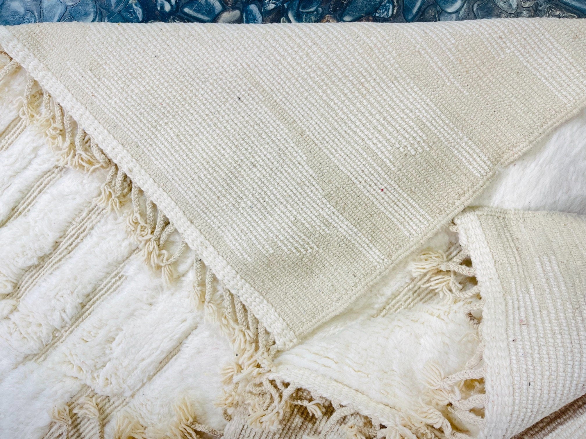 textured neutral colored blanket on blue stones