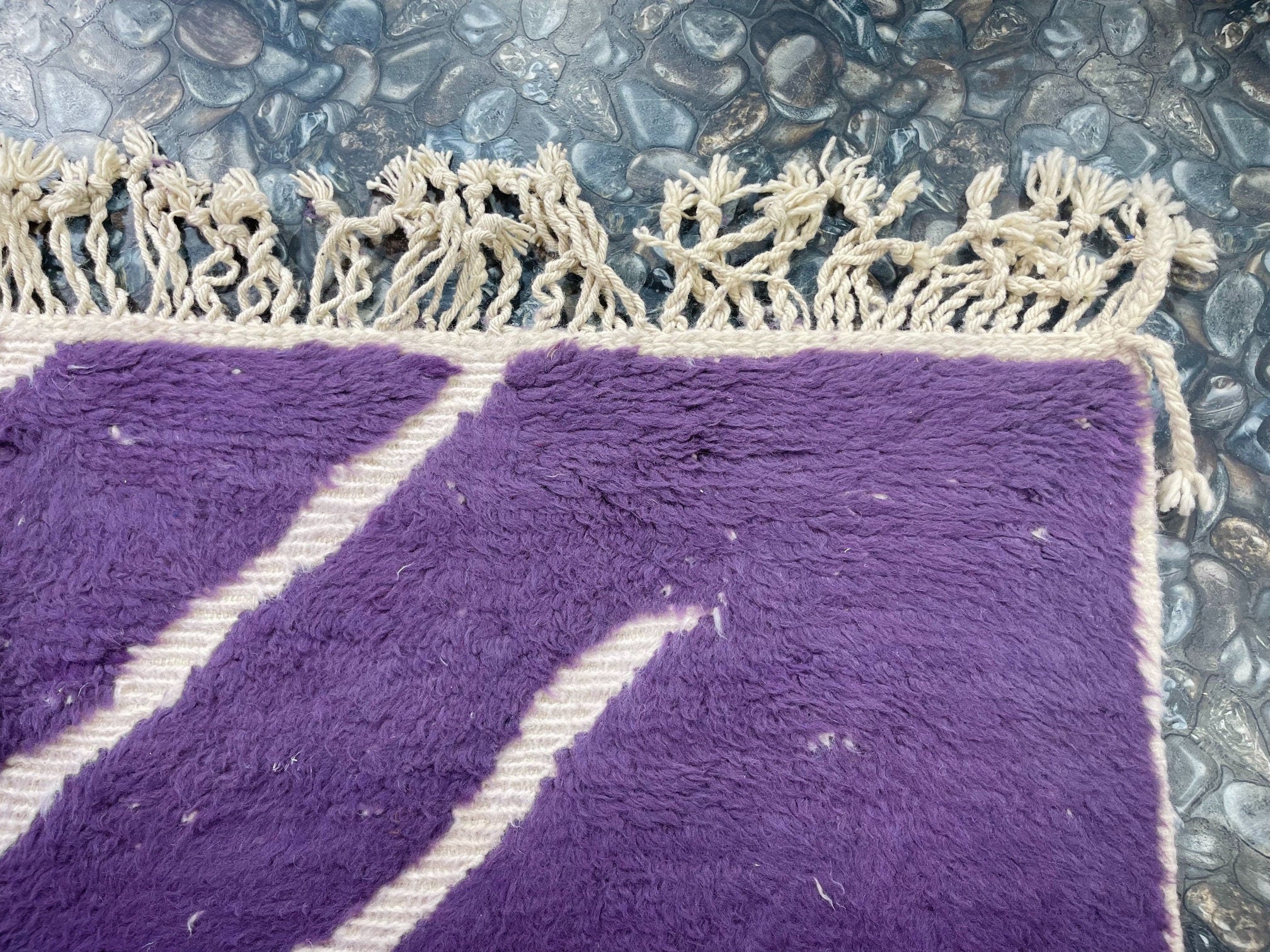 purple textured rug with fringed edges closeup