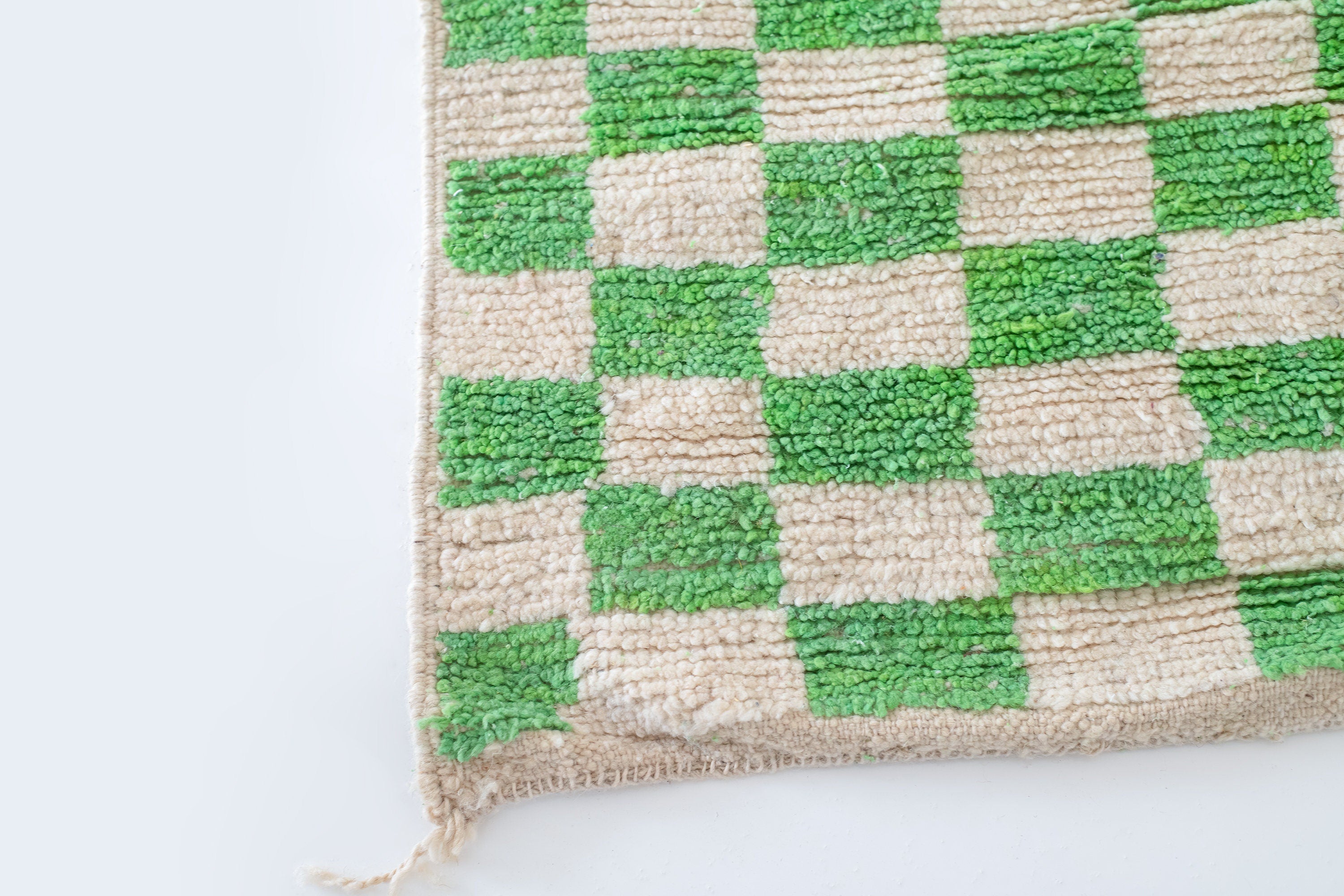 green and beige checkered textured rug corner