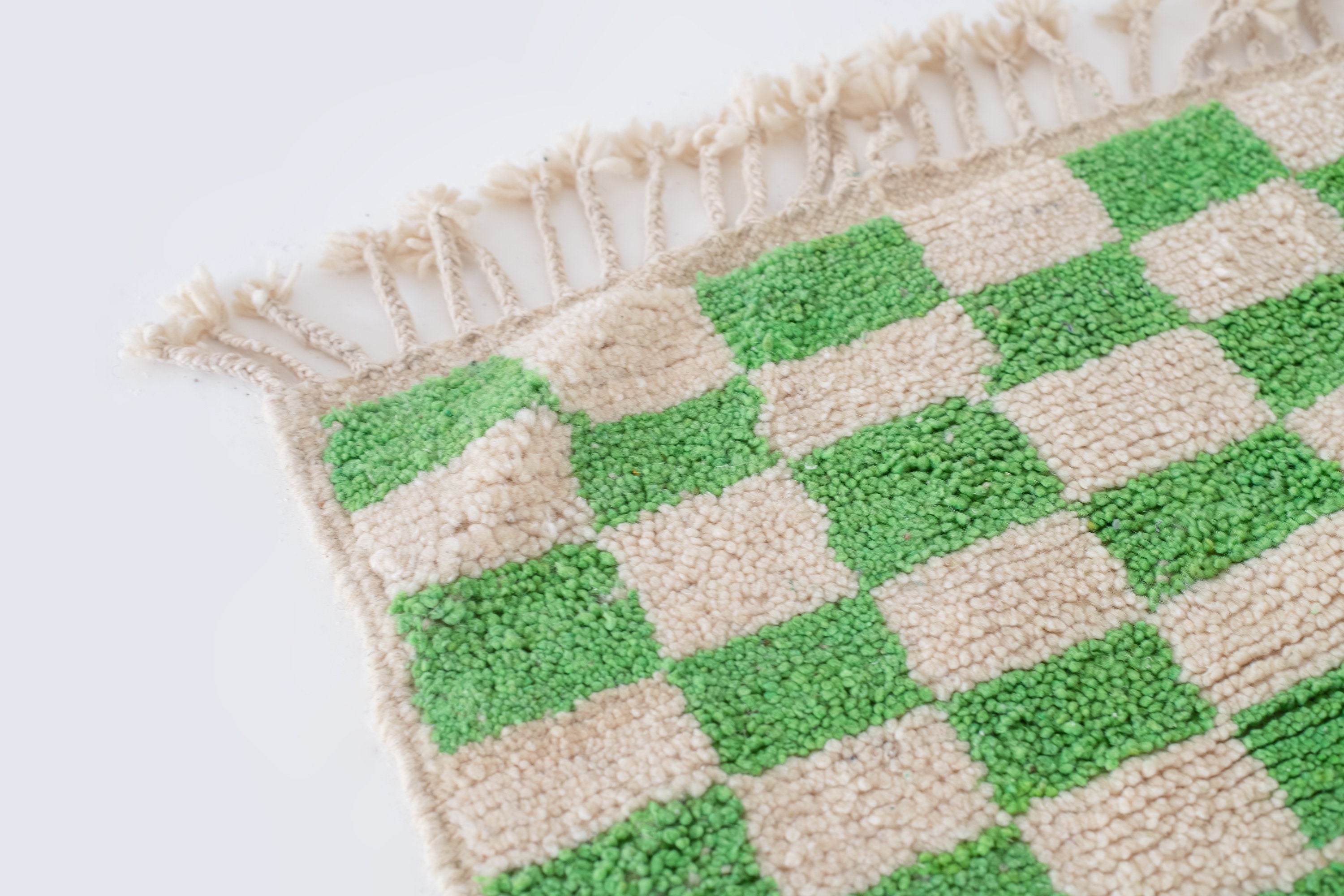 green and beige checkered rug with tassels