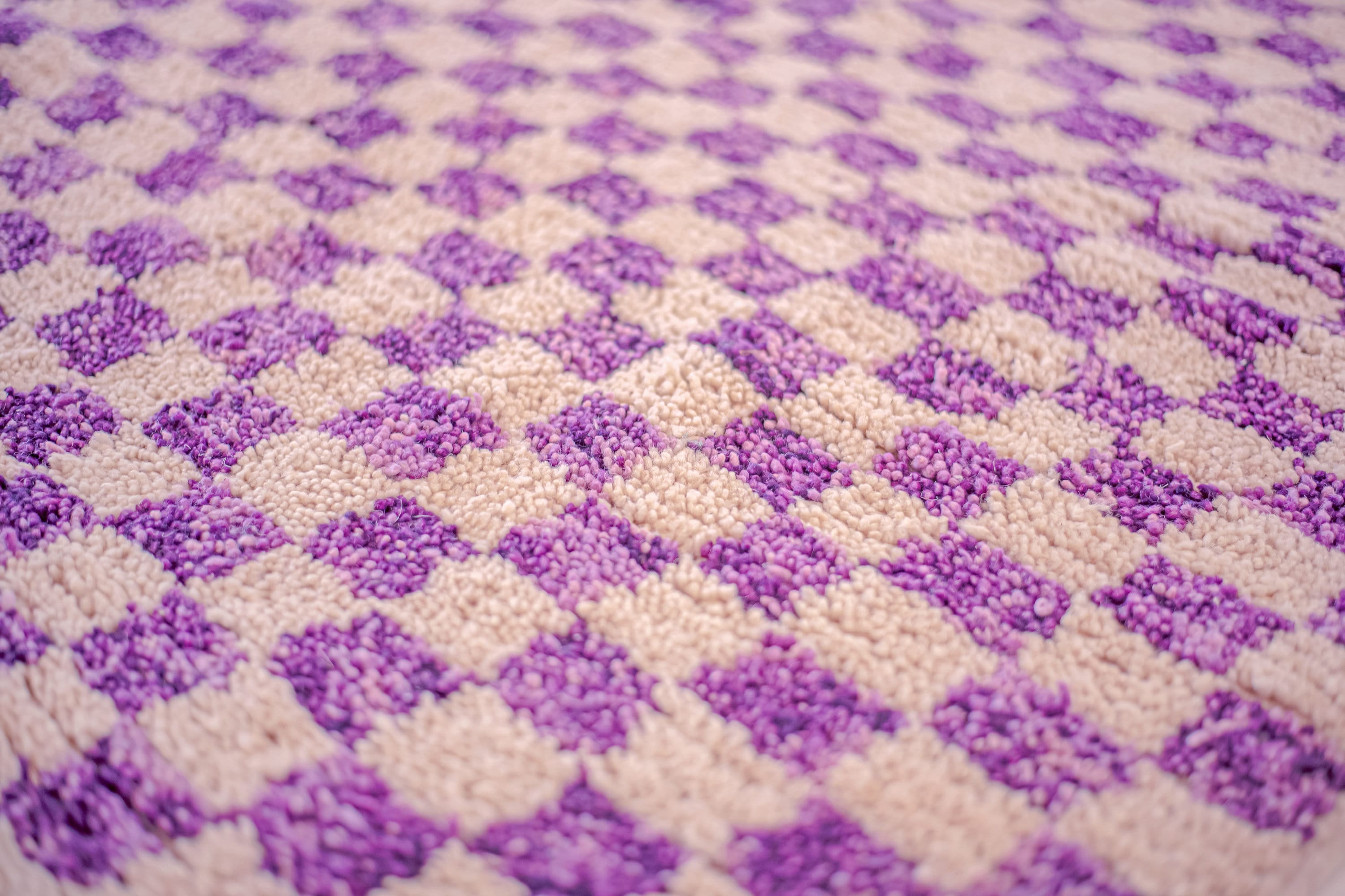 purple checkered rug pattern on textured surface