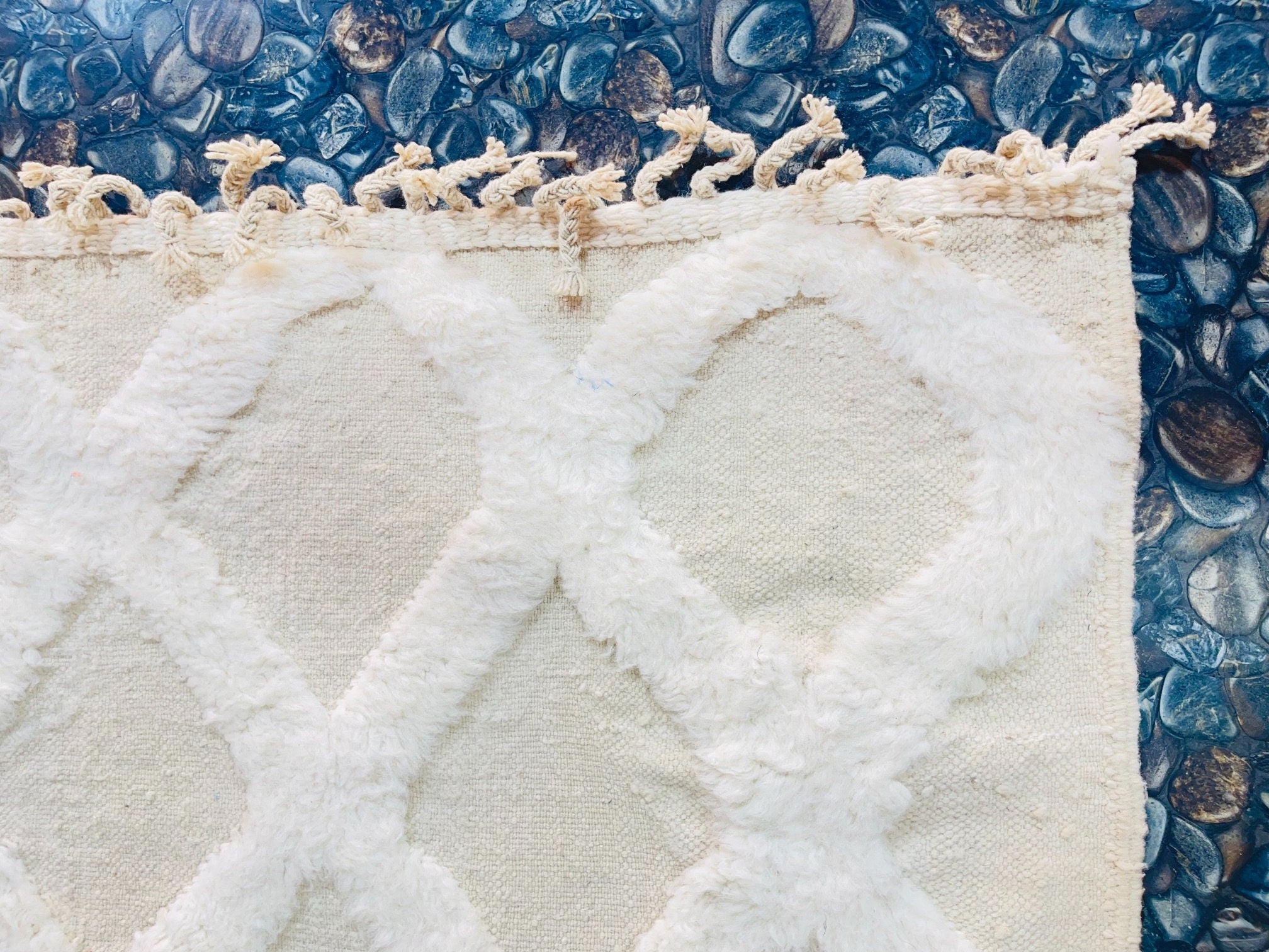 textured cream rug on pebbled background