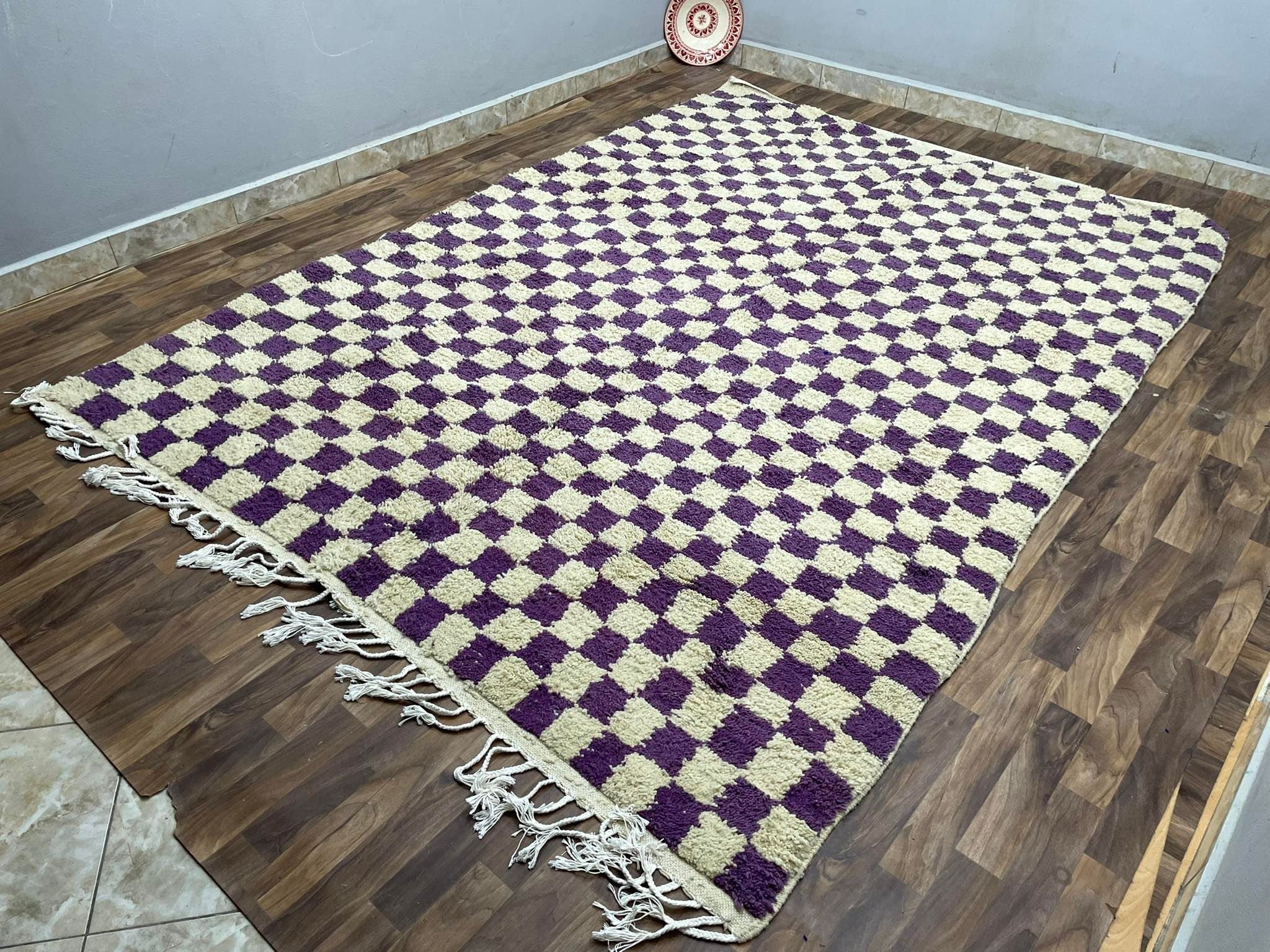 Handwoven purple and cream checkered area rug with tassels, perfect for home decor.